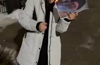 A young woman lights up portrait of Khamenei in Iran.