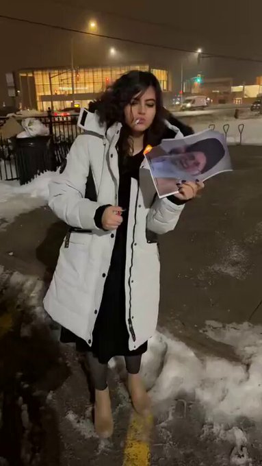A young woman lights up portrait of Khamenei in Iran.