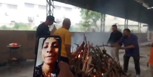 A woman watches last rites of her father on her mobile phone.