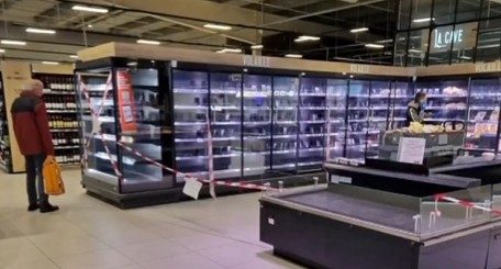 An empty refrigerated supermarket aisle with display cases cleared after a cyberattack disabled the cooling systems.